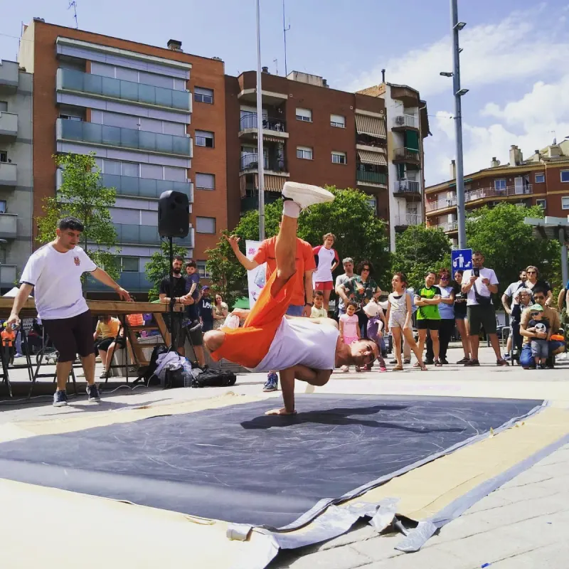 Un ballarí amb pantalons taronja fent un freeze sobre una mà davant del públic